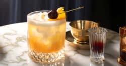Amaretto Sour cocktail with cherry garnish against red background