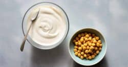 Aquafaba whipped in bowl next to bowl of chickpeas