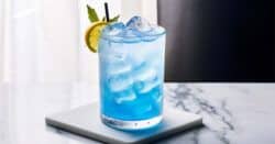 Blue Cowboy drink with mint and orange garnish