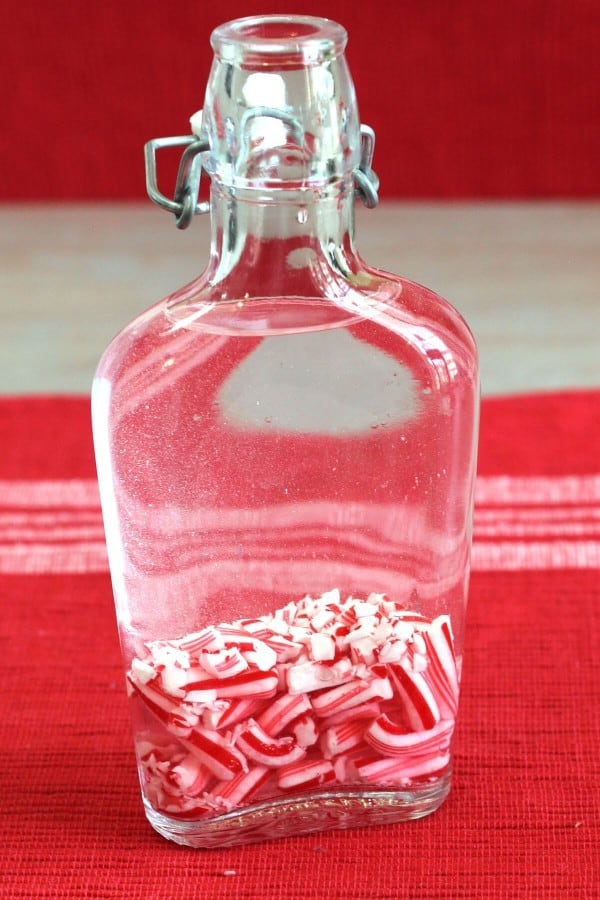 Glass flask containing crushed candy canes and vodka