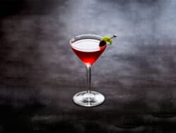 Charlie Chaplin cocktail with cherry and lime peel garnish