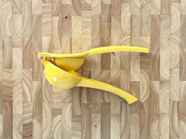 Yellow citrus squeezer on wooden cutting board