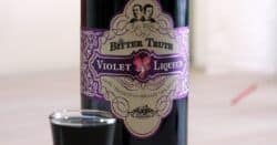 Bottle of Creme de Violette next to shot glass of same