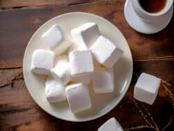 Homemade marshmallows on white plate on wooden table