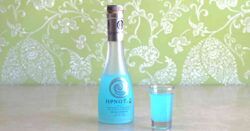 Bottle of Hpnotiq on table with shot glass of same