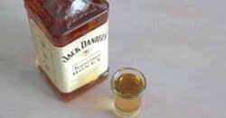 Overhead view of bottle of Jack Daniels Tennessee Honey next to shot glass of same