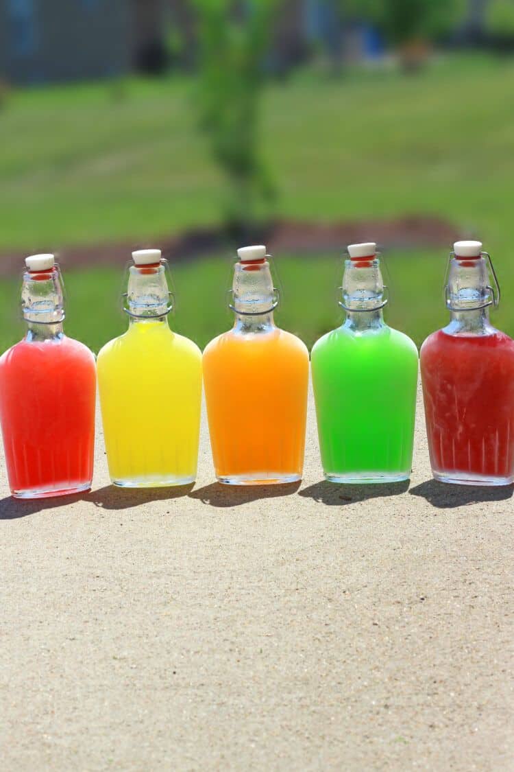 Chilled Skittles Vodka in flasks side by side on concrete patio
