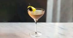 Tuxedo cocktail in coupe glass with orange twist and cherry